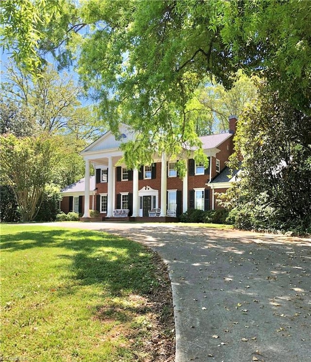 neoclassical home featuring a front lawn