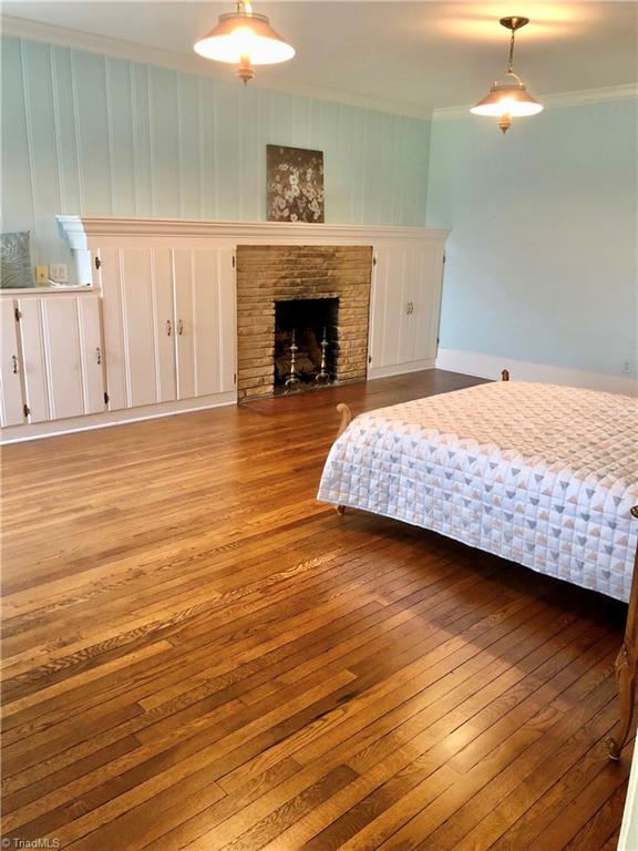 bedroom featuring ornamental molding, light wood-type flooring, and a fireplace