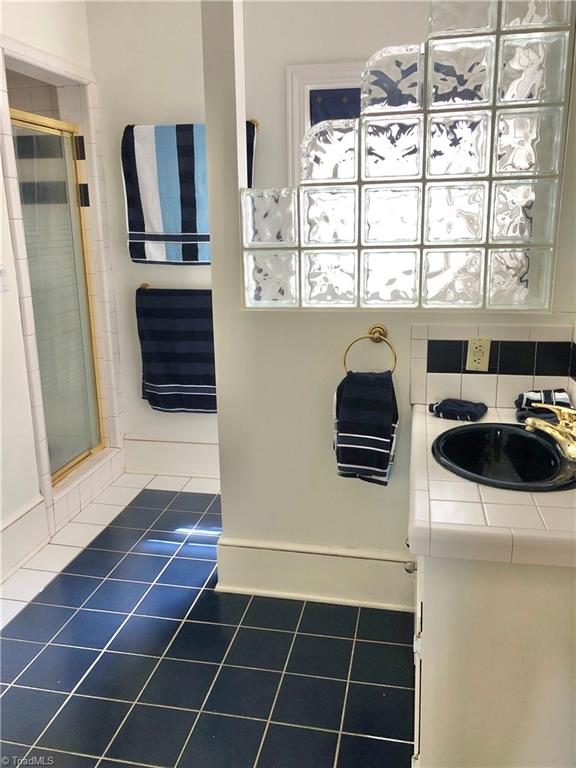 bathroom with walk in shower, vanity, tile patterned flooring, and tasteful backsplash