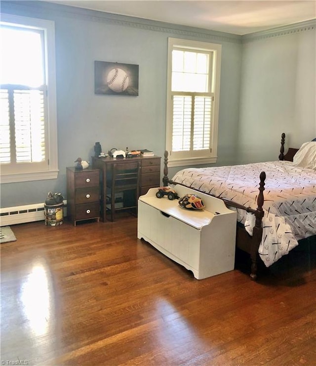 bedroom with a baseboard heating unit, crown molding, dark wood-type flooring, and multiple windows