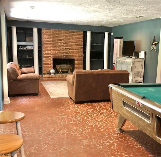 recreation room with a brick fireplace, a textured ceiling, and pool table