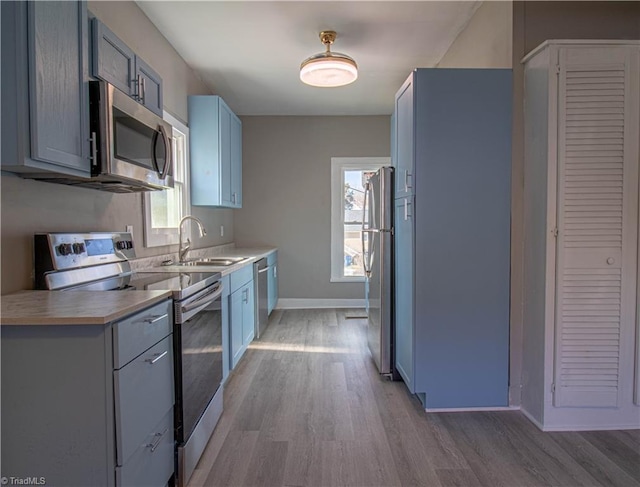 kitchen with a wealth of natural light, appliances with stainless steel finishes, sink, and light hardwood / wood-style flooring