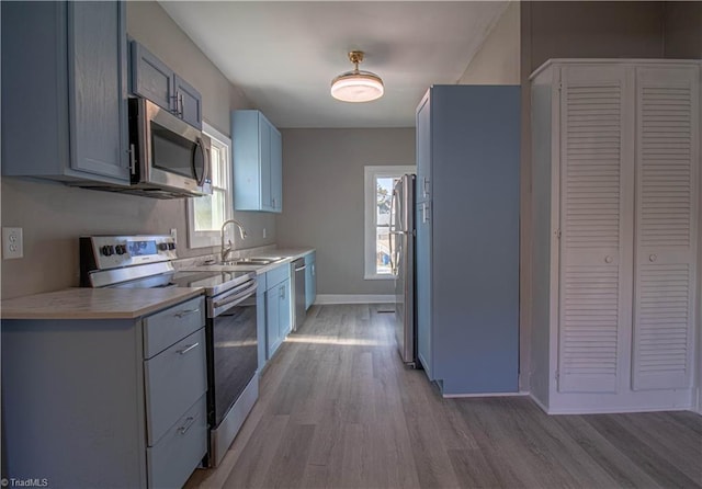 kitchen featuring sink, a wealth of natural light, light hardwood / wood-style flooring, and stainless steel appliances