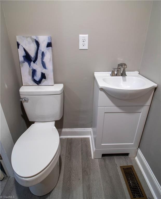 bathroom with toilet, vanity, and wood-type flooring