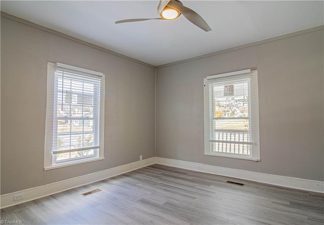 empty room featuring ceiling fan, crown molding, and wood-type flooring