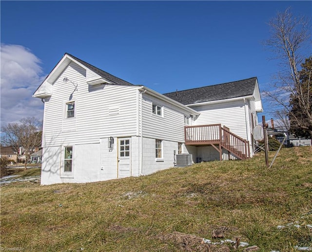 rear view of property with a wooden deck, a lawn, and central AC