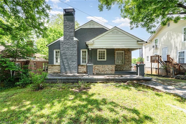 rear view of property with stone siding, a lawn, a chimney, and a porch