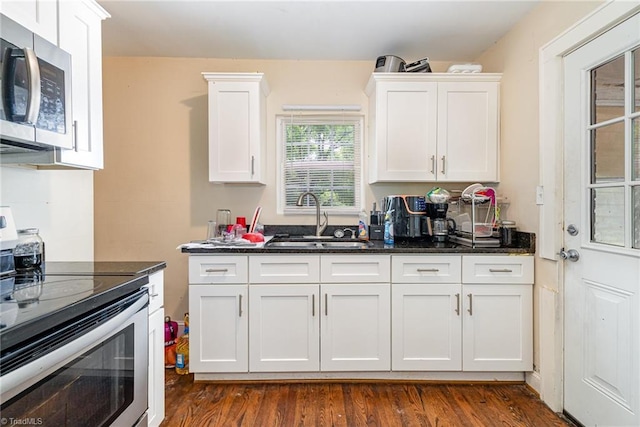 kitchen featuring stainless steel appliances, a sink, white cabinets, and dark wood finished floors