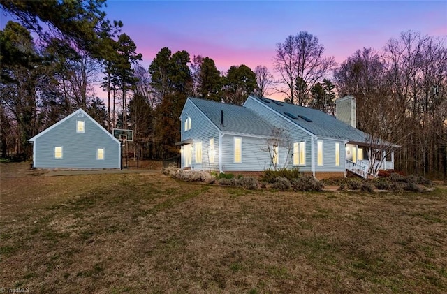 back of house with a chimney and a yard