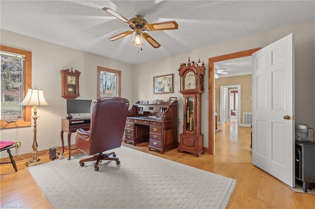 office area with light wood finished floors, visible vents, a ceiling fan, a textured ceiling, and baseboards