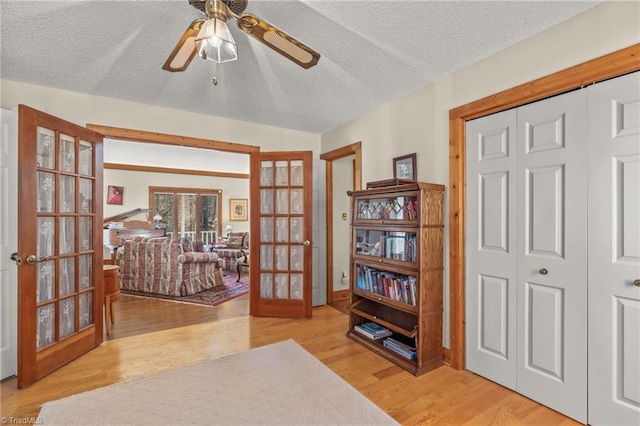 interior space featuring light wood finished floors, ceiling fan, a textured ceiling, and french doors