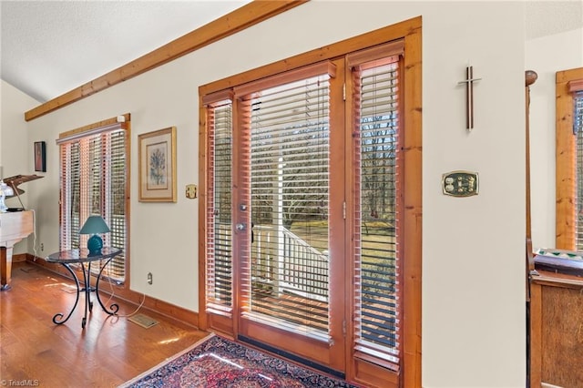 interior space with a wealth of natural light, a textured ceiling, baseboards, and wood finished floors