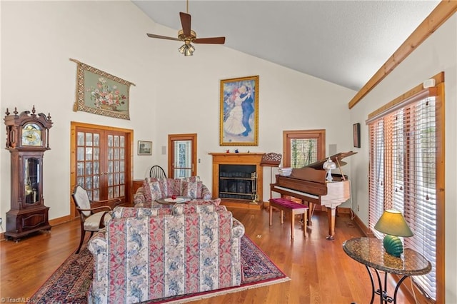 living room featuring high vaulted ceiling, a glass covered fireplace, wood finished floors, and french doors