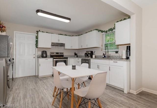 kitchen with appliances with stainless steel finishes, sink, light wood-type flooring, and white cabinetry