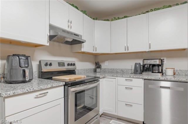 kitchen with light stone counters, white cabinets, and stainless steel appliances