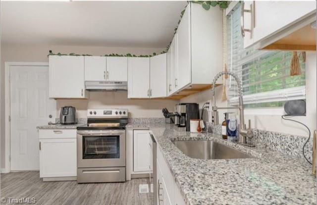 kitchen with light hardwood / wood-style flooring, sink, stainless steel appliances, light stone countertops, and white cabinetry