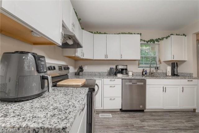 kitchen featuring appliances with stainless steel finishes, white cabinetry, sink, and light hardwood / wood-style flooring