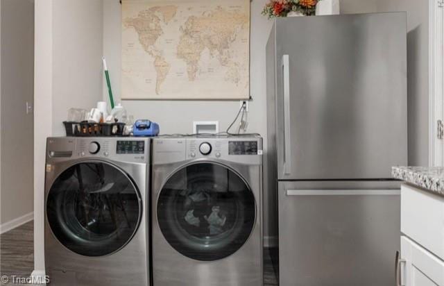 clothes washing area featuring cabinets, hardwood / wood-style floors, and washer and dryer