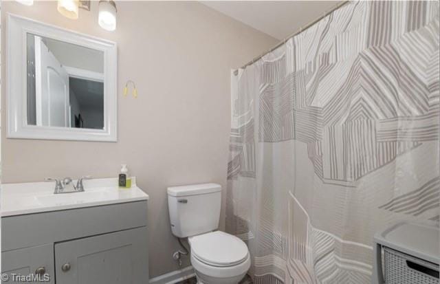 bathroom featuring vanity, walk in shower, and toilet