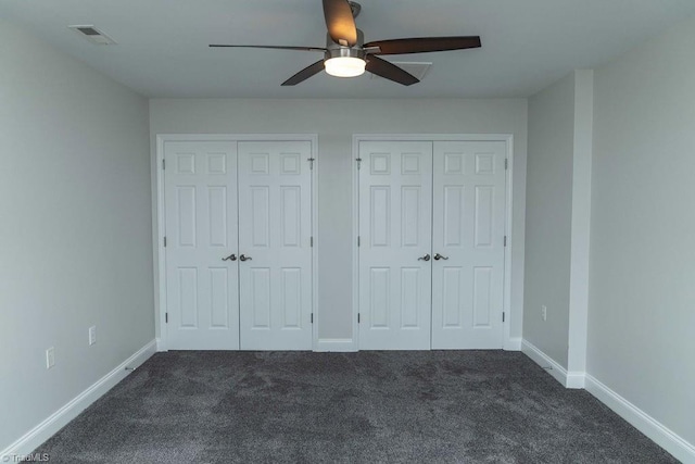 unfurnished bedroom featuring multiple closets, ceiling fan, and dark colored carpet