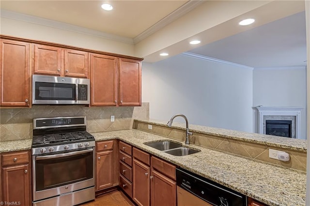 kitchen with sink, light stone counters, kitchen peninsula, appliances with stainless steel finishes, and ornamental molding