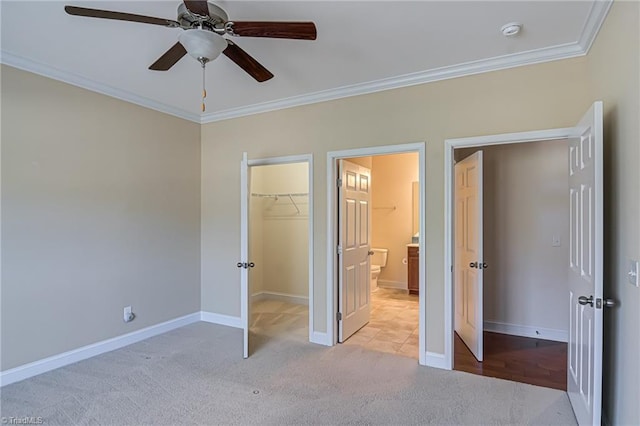 unfurnished bedroom featuring ornamental molding, light colored carpet, ceiling fan, a spacious closet, and a closet