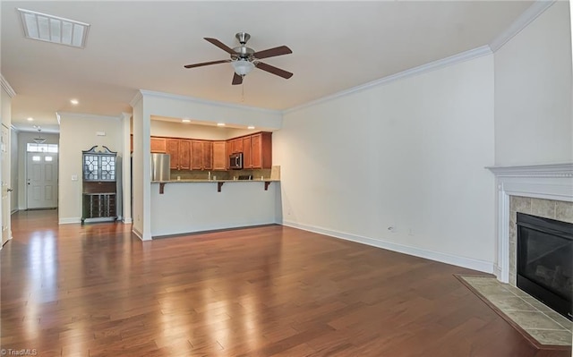 unfurnished living room featuring a tile fireplace, crown molding, and ceiling fan