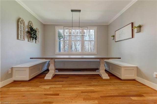 dining area featuring crown molding, light wood finished floors, baseboards, and a chandelier