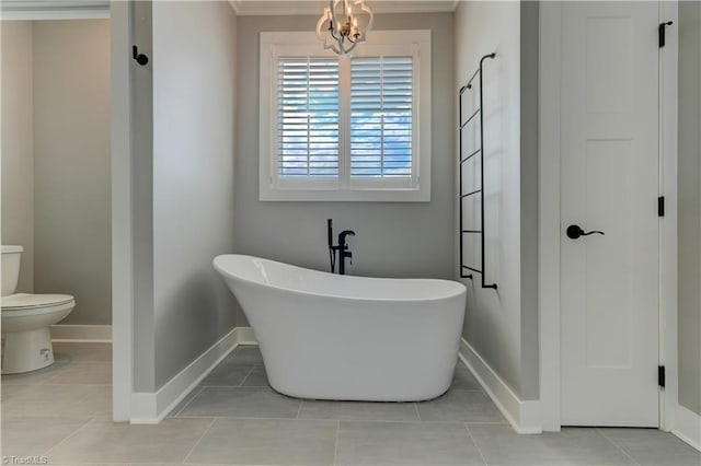 full bath with a freestanding tub, baseboards, toilet, ornamental molding, and tile patterned flooring