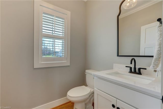 bathroom featuring baseboards, vanity, toilet, wood finished floors, and ornamental molding