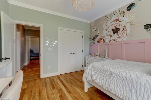 bedroom with crown molding, light wood-style flooring, and a closet
