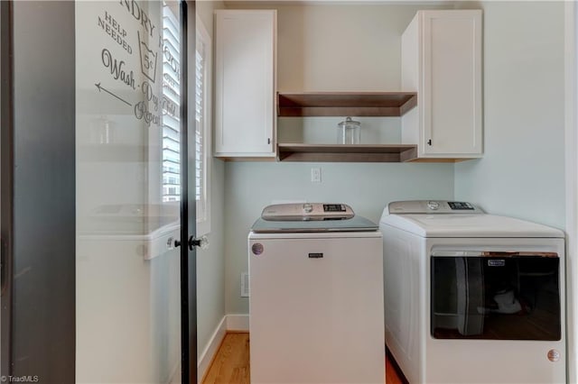 washroom featuring cabinet space, washing machine and clothes dryer, and light wood-style floors