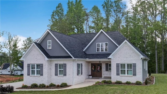 craftsman-style house with a front lawn, a shingled roof, brick siding, and board and batten siding