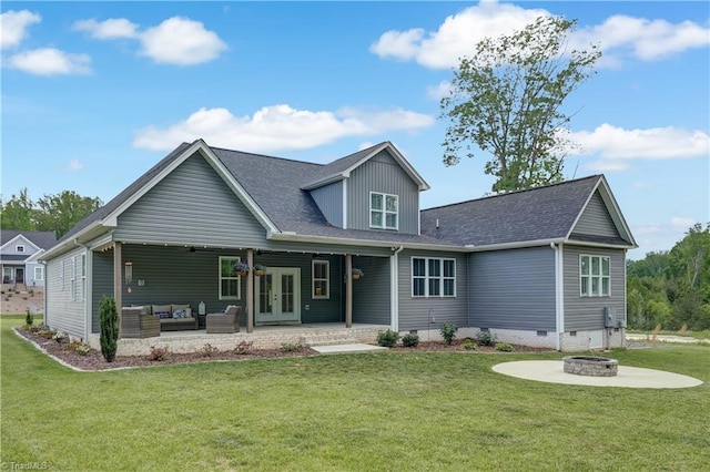 view of front of house with french doors, an outdoor living space with a fire pit, a front lawn, a patio area, and a shingled roof