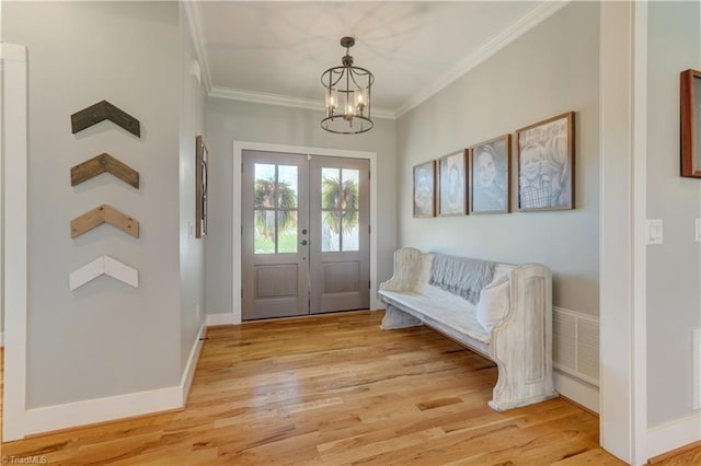 entrance foyer with ornamental molding, light wood-style floors, french doors, a chandelier, and baseboards