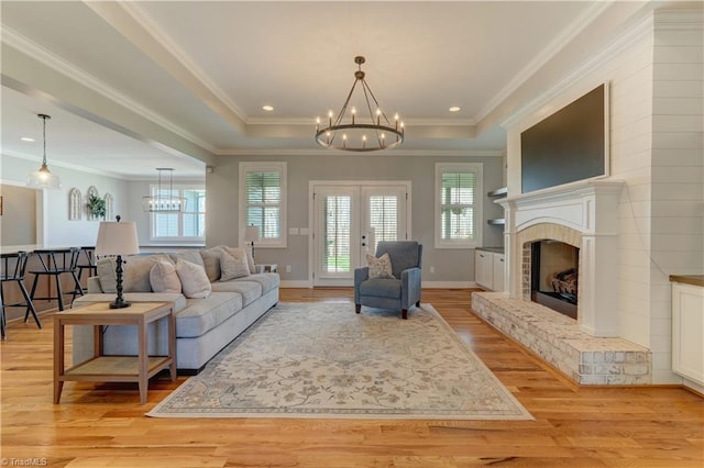 living area with a chandelier, healthy amount of natural light, light wood-style flooring, ornamental molding, and french doors