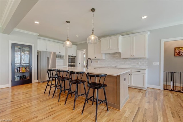 kitchen with stainless steel appliances, white cabinetry, decorative backsplash, crown molding, and a kitchen breakfast bar