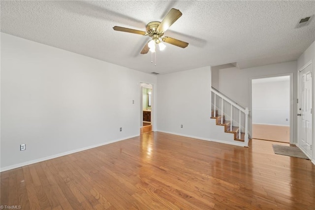 empty room with ceiling fan, a textured ceiling, and light wood-type flooring