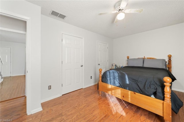 bedroom with ceiling fan, light hardwood / wood-style floors, and a textured ceiling