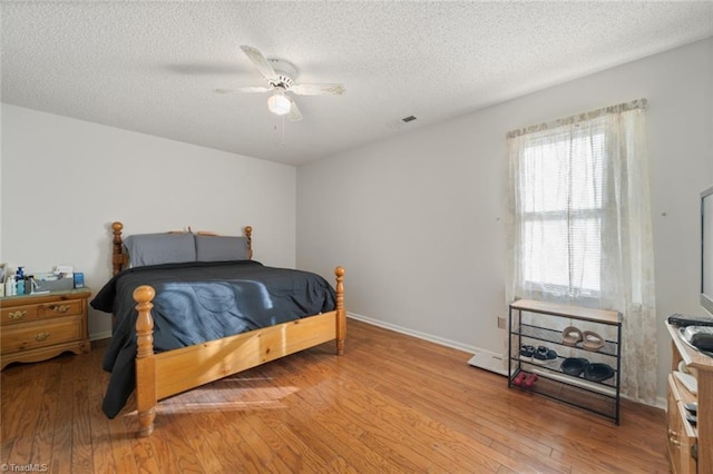 bedroom featuring ceiling fan, light hardwood / wood-style floors, and a textured ceiling