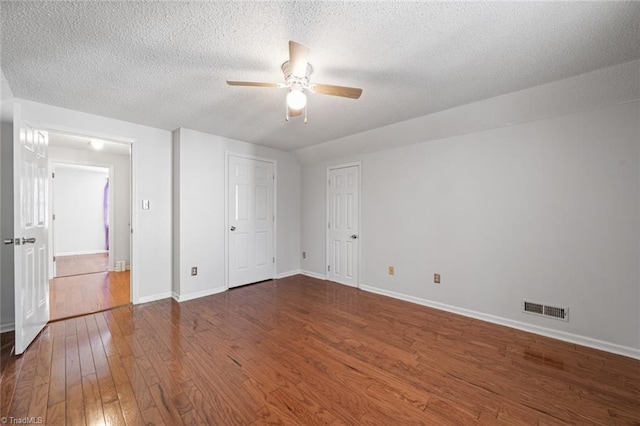 unfurnished bedroom featuring ceiling fan, dark hardwood / wood-style floors, and a textured ceiling