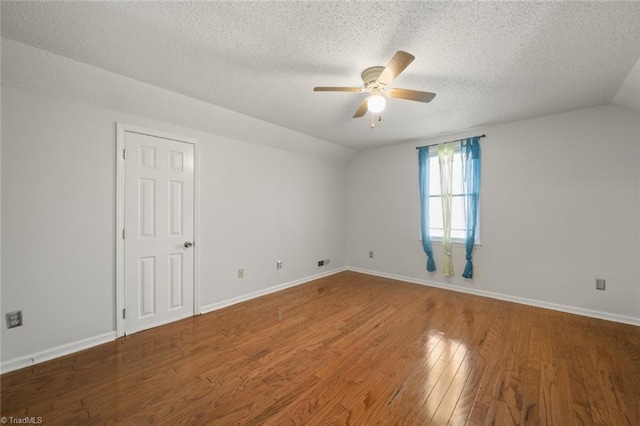 spare room featuring hardwood / wood-style flooring, vaulted ceiling, a textured ceiling, and ceiling fan