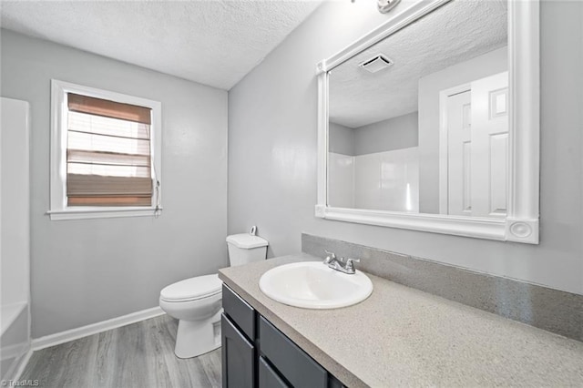 full bathroom with hardwood / wood-style floors, shower / bathtub combination, vanity, toilet, and a textured ceiling