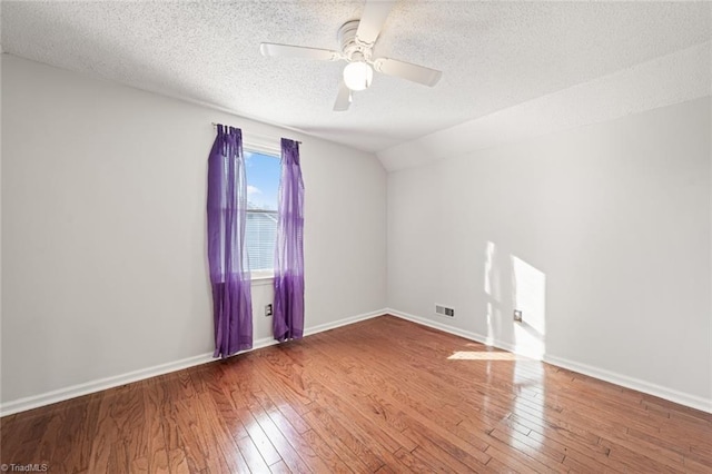 spare room with lofted ceiling, ceiling fan, hardwood / wood-style flooring, and a textured ceiling