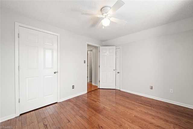 unfurnished bedroom with ceiling fan, wood-type flooring, and a textured ceiling