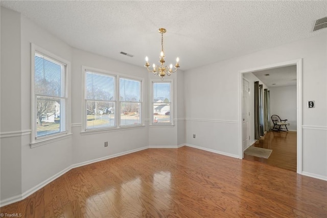 unfurnished room featuring wood-type flooring, a chandelier, and a textured ceiling