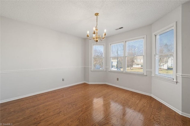 spare room featuring hardwood / wood-style flooring, a notable chandelier, and a textured ceiling