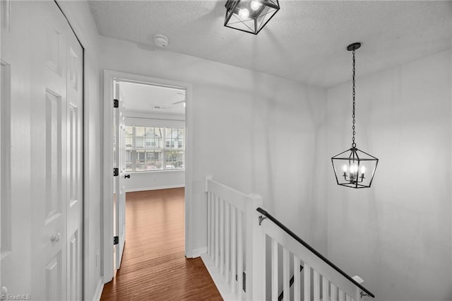 1948 Ray Alexander Dr, Greensboro, NC 27410 - corridor with an upstairs landing, a chandelier, a textured ceiling, dark wood finished floors, and baseboards