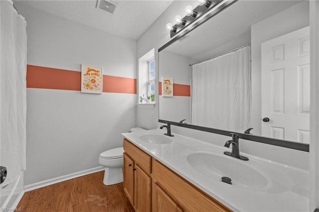 1948 Ray Alexander Dr, Greensboro, NC 27410 - full bath with wood finished floors, toilet, a shower with shower curtain, baseboards, and double vanity