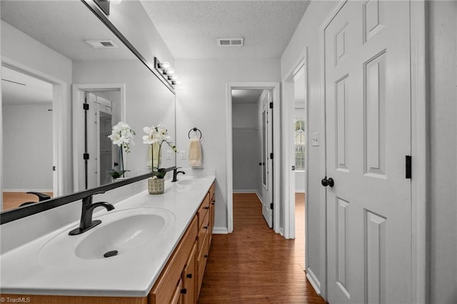 1948 Ray Alexander Dr, Greensboro, NC 27410 - bathroom with wood finished floors, double vanity, a textured ceiling, and baseboards